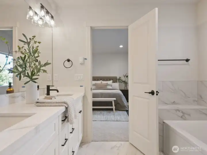 Beautiful dual vanity with quarts counter and Undermount sinks in Primary Bathroom.  Check out the tile floors and tile tub surround.