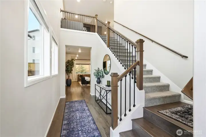 Bright and welcoming entry foyer with modern staircase, luxury vinyl plank flooring, and open sightlines creating a spacious first impression inside this Covington Washington home for sale.