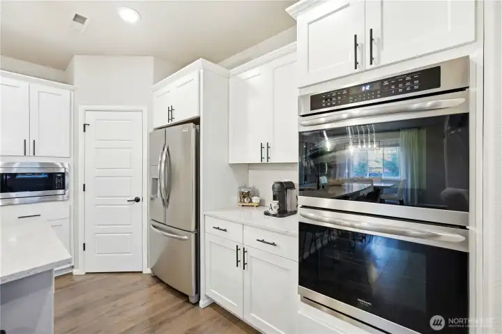 Chef inspired kitchen in this Covington WA home for sale featuring stainless steel appliances, double ovens, modern cabinetry, and ample prep space.