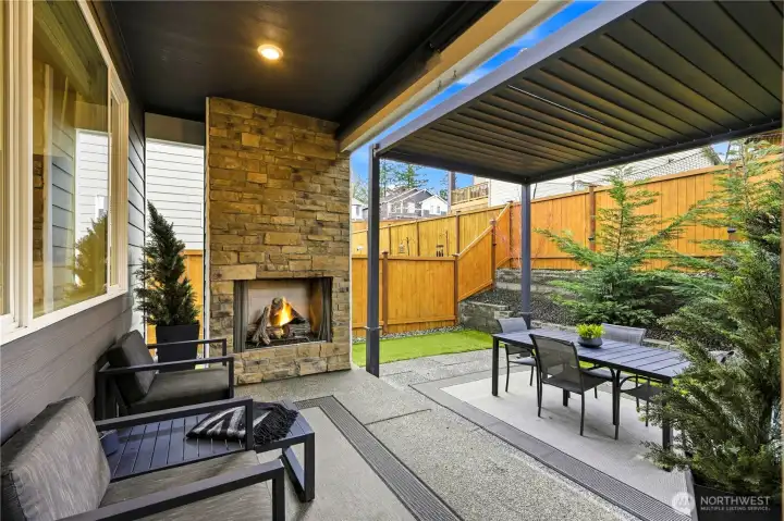 Covered outdoor living space with gas fireplace, creating a year round entertaining area in the backyard of this Covington WA home for sale.