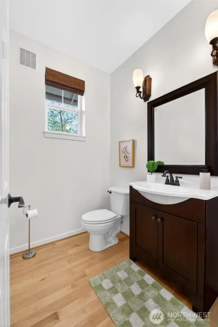 Conveniently located on the main level, this well-appointed powder room features clean lines, warm wood cabinetry, and natural light from an upper window, creating a bright and polished space for guests.