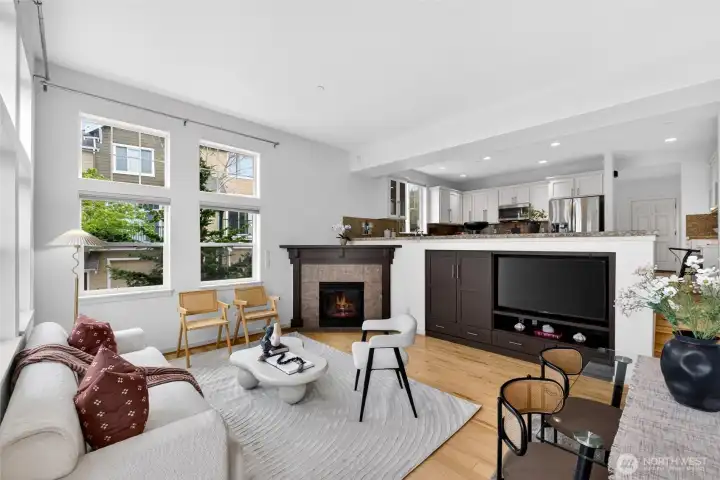 Comfortable living room anchored by a fireplace and custom built-in media cabinetry, offering both warmth and practical storage. Large windows bring in steady natural light, creating a relaxed setting for everyday living or unwinding at the end of the day.