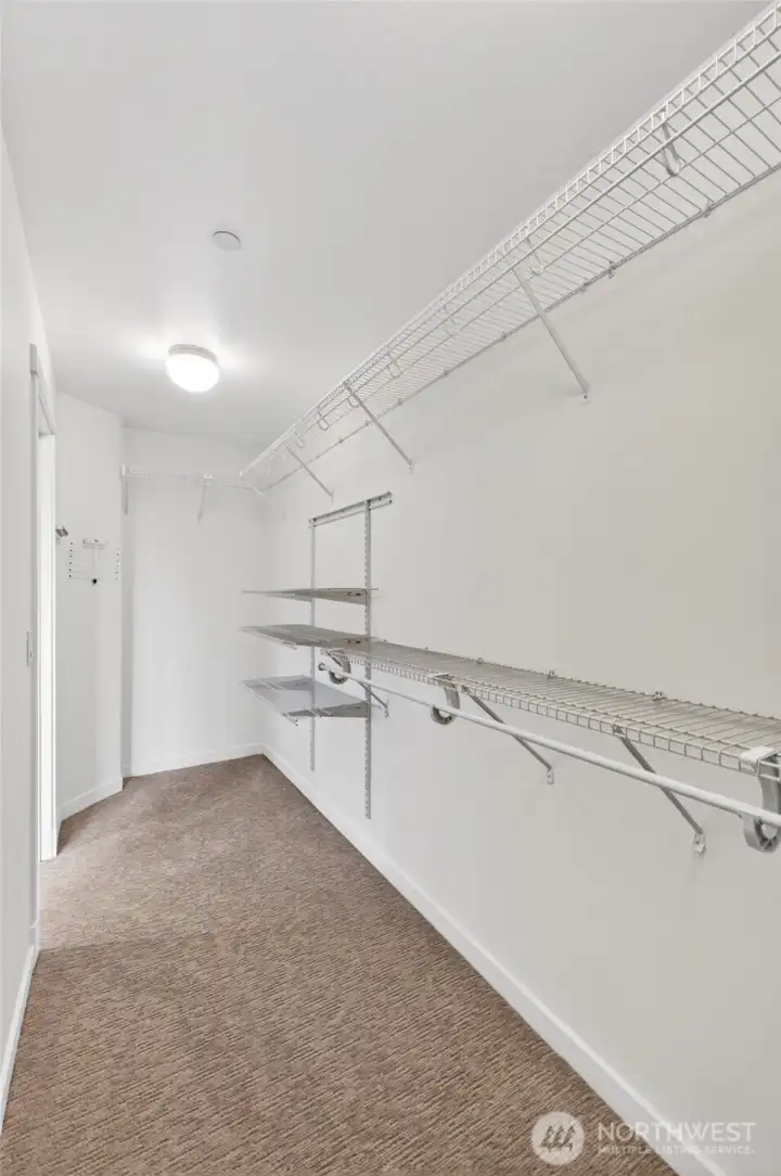 An oversized walk-in closet delivers an impressive amount of storage, offering extensive hanging space, shelving, and flexibility for organization. The size alone sets it apart from what is typically found in townhome living.