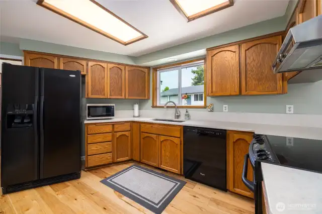 Another view of gorgeous kitchen with large fridge and stunning, durable hickory flooring.