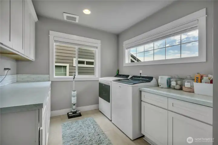 Upstairs laundry room with ample counter space and cabinet storage.