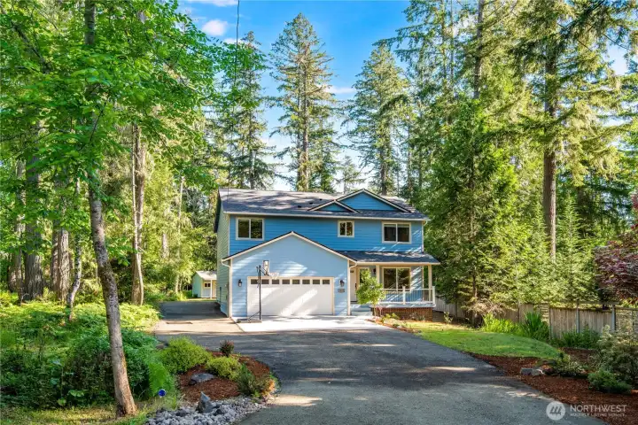 Front exterior of custom waterfront home nestled among mature evergreens.
