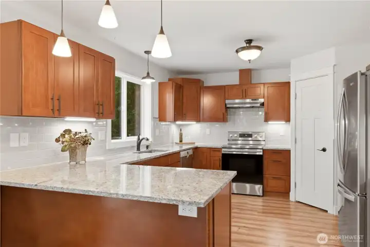 Open-concept kitchen with granite counters and stainless appliances.