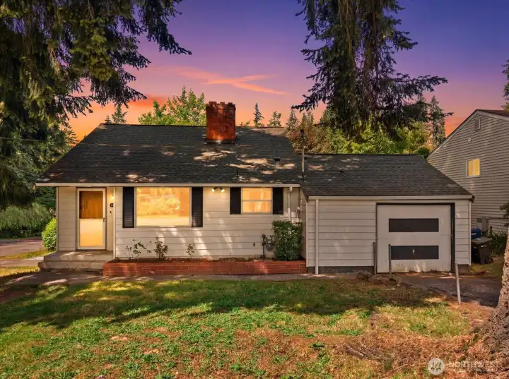 As the sun sets, this classic home takes on a whole new charm. Mature evergreens frame the property, while the warm glow from inside highlights the welcoming character and timeless curb appeal. Virtual twilight image for marketing purposes.