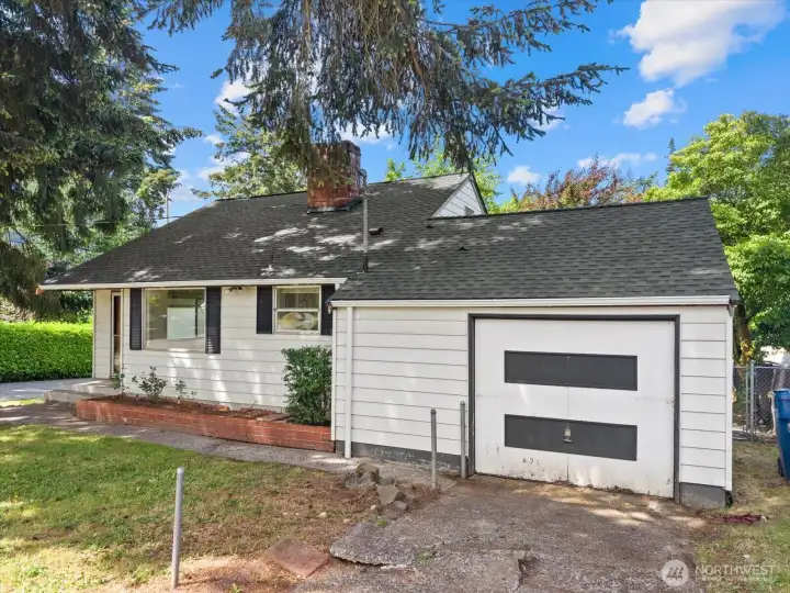 The attached garage and generous driveway provide everyday convenience, while the established landscaping and towering trees create a sense of privacy from the moment you arrive.