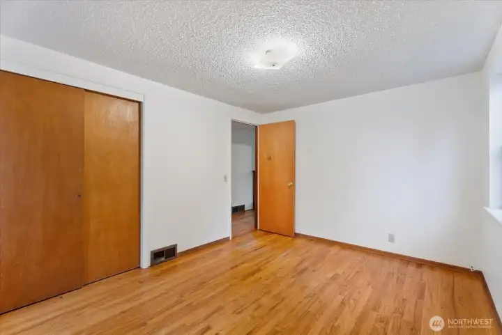 Main-floor bedroom featuring hardwood floors, a spacious closet, and natural light, creating a comfortable retreat with room to make it your own.