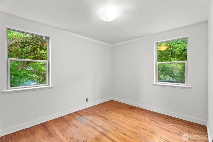 Second main floor bedroom showcasing hardwood floors and abundant natural light.