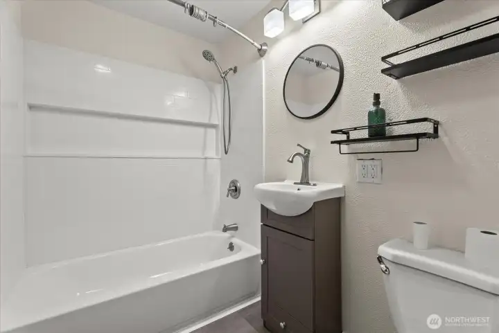 Updated bathroom featuring a tub and shower combination, tiled surround, and modern vanity.