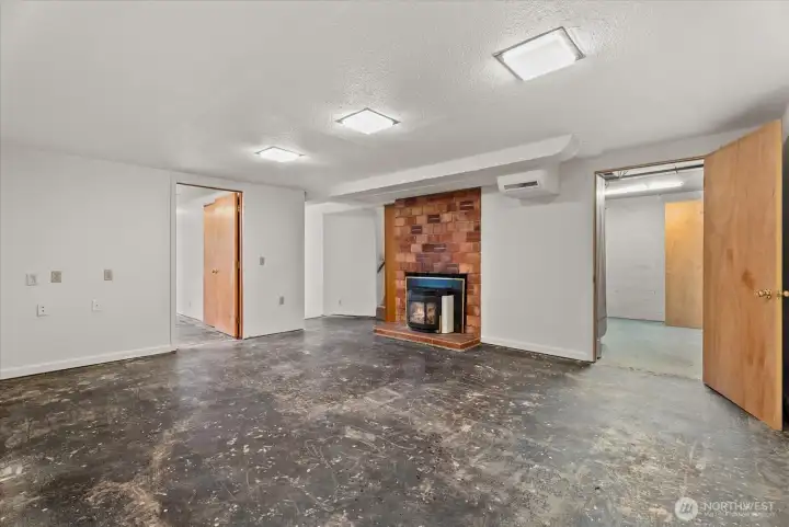 Another view of the spacious lower-level living area, showcasing the fireplace, open layout, and access to adjacent storage spaces.