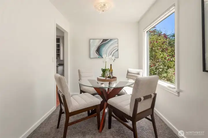 Dining area with large windows and entry to kitchen space.