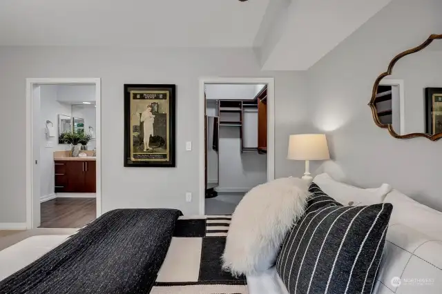 Luxurious and spacious primary bedroom features a large picture window looking out to the deck and beyond. Ceiling fan, large walk-in closet and en suite complete the space.