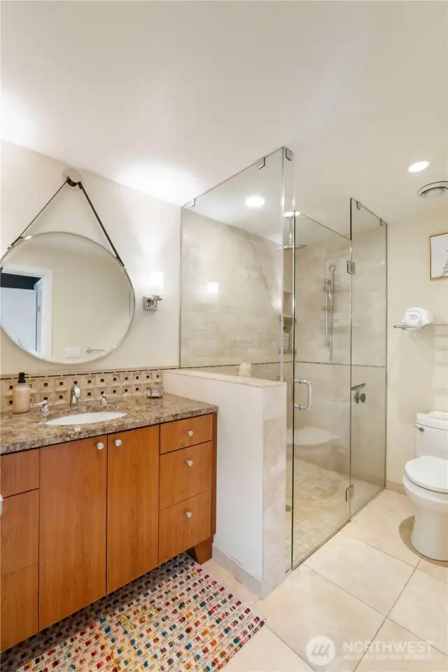 The main level bath has a large vanity with granite countertop, tile flooring and a spacious step in shower with tile surround