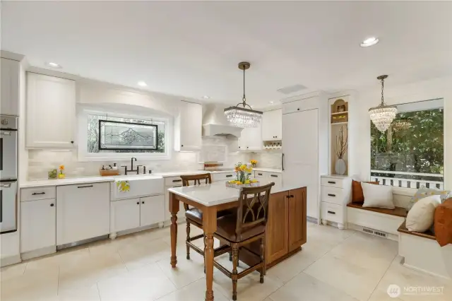 The gorgeous kitchen is fit for a chef and overlooks the outdoor dining space and secret garden courtyard. Detailed stone floors, a quartz topped island, bench seating & sparkling chandeliers add beauty to the function