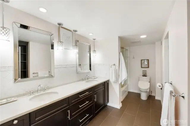 The upper primary bath features an enormous marble topped counter with double sinks, tile backsplash, tons of cabinetry, tile flooring and custom accents.