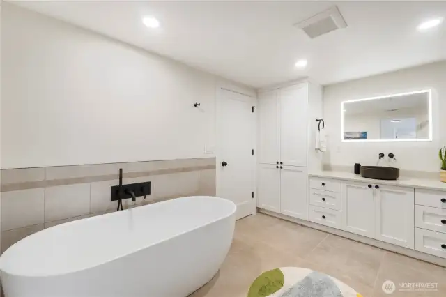 Tons of beautiful cabinetry, a lighted hotel mirror plus tile flooring & surround accents the lower level bath