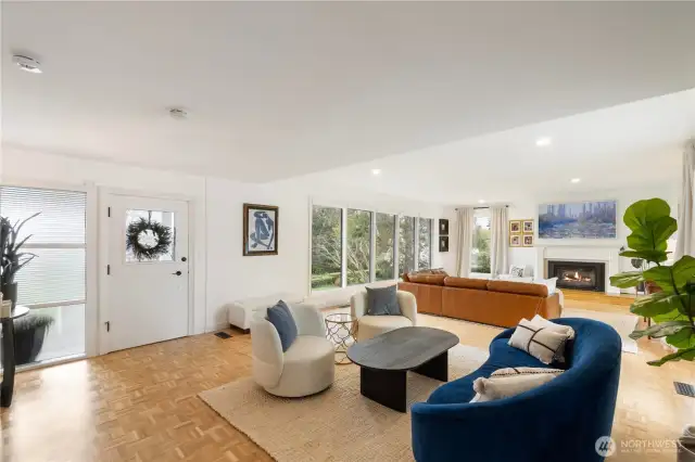 The front door welcomes you into the grand living space with a cozy fireplace and windows with sweeping views of the sound and the lovely landscape