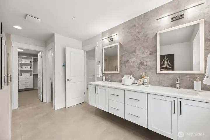 Spa-like primary with extensive tile, floating vanity, back lit mirrors, and heated floors