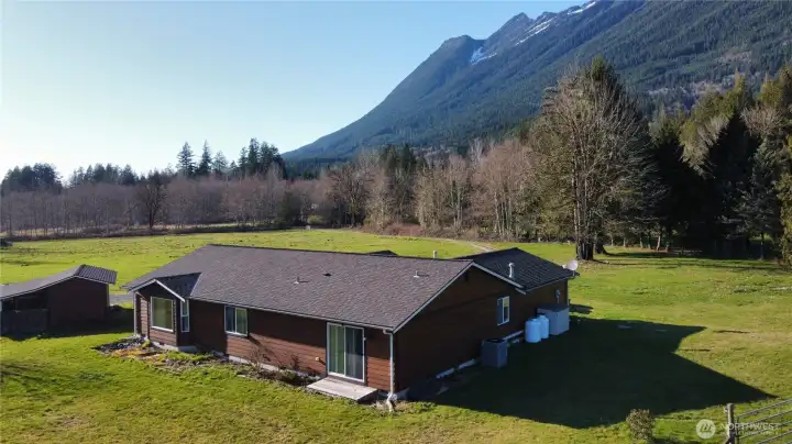 Aerial view of back of the house, looking toward 371st Ave NE, and the mountains in the background.