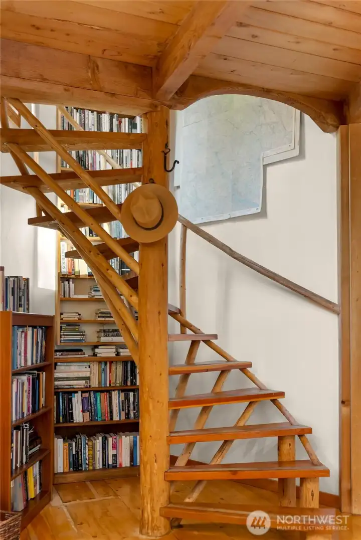 The artistic wooden spiral stair leads to the sunlit upstairs.