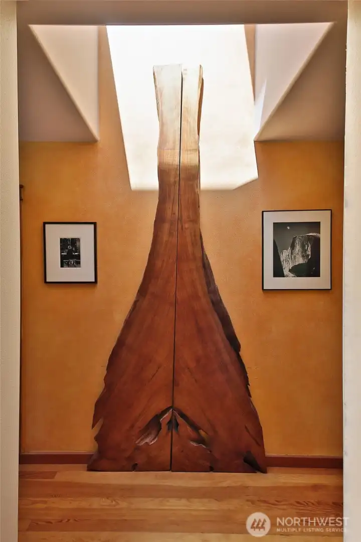 An old growth live edge Cedar stands tall in the hallway that leads to the Primary Suite, Family Room, Office & Laundry Room. Take a moment to appreciate this artistic feature. Lets turn left to the Primary Suite.... An old growth live edge Cedar stands tall in the hallway that leads to the Primary Suite, Family Room, Office & Laundry Room. Take a moment to appreciate this artistic feature. Lets turn left to the Primary Suite....