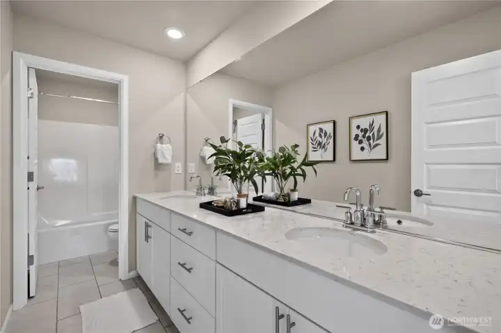 Upstairs bathroom featuring a spacious double vanity, large mirror, ample cabinet storage, and a tub-and-shower combination.