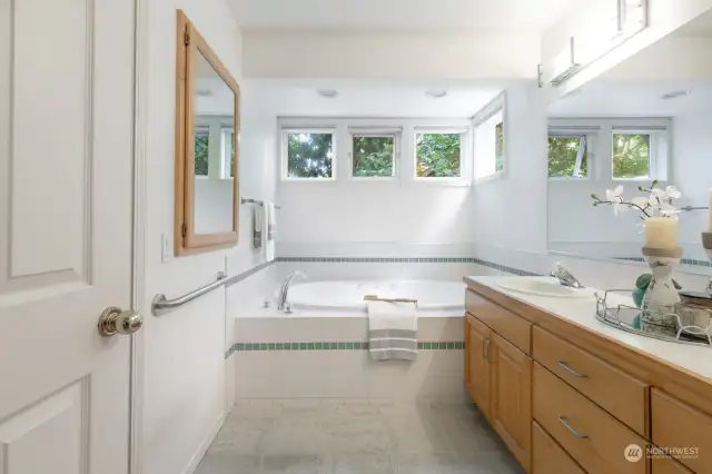 Tiled Primary bathroom with large jetted tub and double vanity.