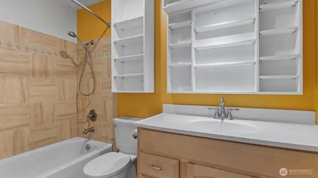 The bathroom has a large counter and a ton of shelving.