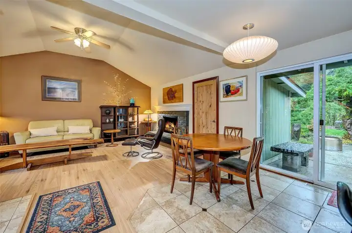 Another View Of The Family Room With Wood Burning Fireplace, Tiled Flooring And Slider To Backyard Oasis.