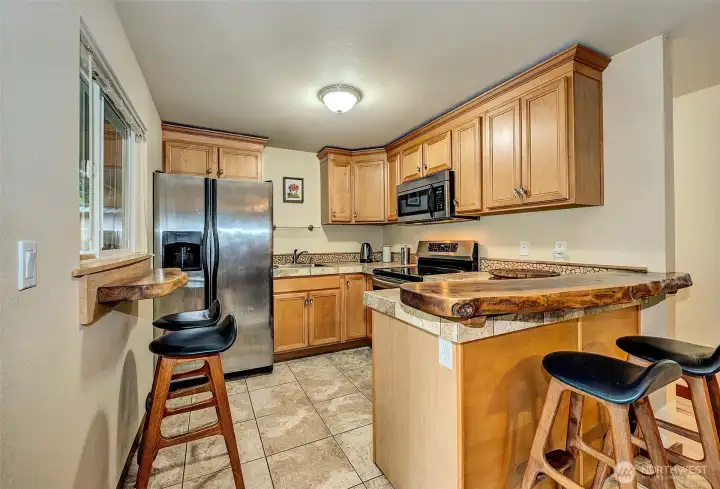 Custom Kitchen w/Stainless Appliances, Tiled Flooring, And Sitting Bars.