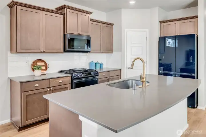 Kitchen features island with quartz counter tops and a Navy Blue stainless appliance package.