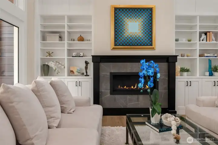 The living room feels both dramatic and inviting, with soaring ceilings, a gas fireplace for cozy evenings, and direct access to a spacious deck that extends the living space outdoors—perfect for entertaining, dining al fresco, or simply enjoying the peaceful natural surroundings.