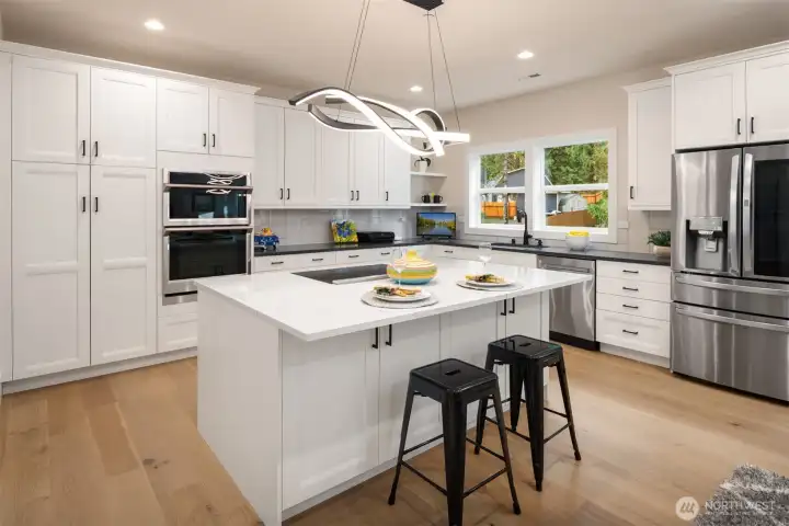 The finishes throughout are upscale and high-end, giving the home a polished custom feel from top to bottom. The gourmet kitchen is both beautiful and functional, featuring quartz slab counters, custom cabinetry, stainless steel appliances, walk-in pantry and an oversized island that anchors the main living spaces.