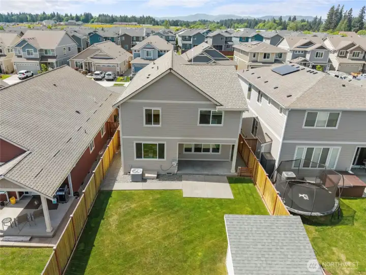 Elevated rear view of the home showcases the generous backyard footprint, covered patio,  and the custom shed in the back corner.