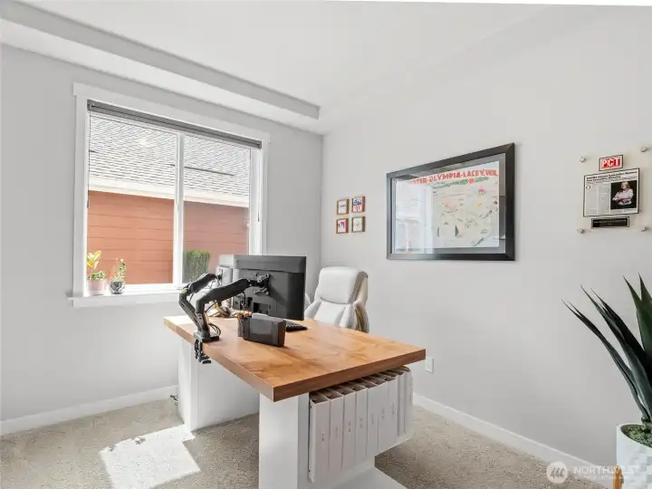 Flexible main-floor home office with french doors, featuring plush carpet, a bright window, and plenty of wall space. Easily convert to a playroom, or hobby space to suit your lifestyle.