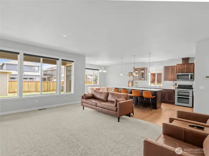 This open-concept living area flows seamlessly into the kitchen and dining spaces, with large windows offering backyard views. The layout is perfect for entertaining, with ample room for oversized furniture and natural light throughout.