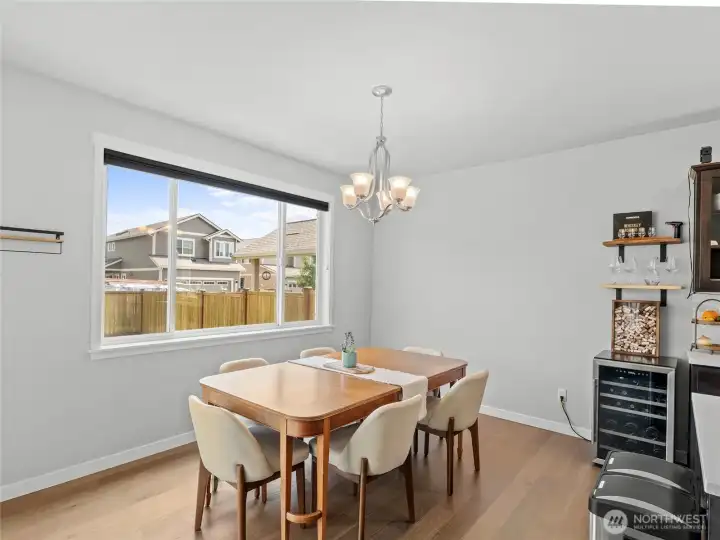 The dining area is bathed in natural light from a large picture window and accented by a classic chandelier. Generous space for a full dining set, and proximity to the kitchen make this an ideal spot for everyday meals and gatherings.