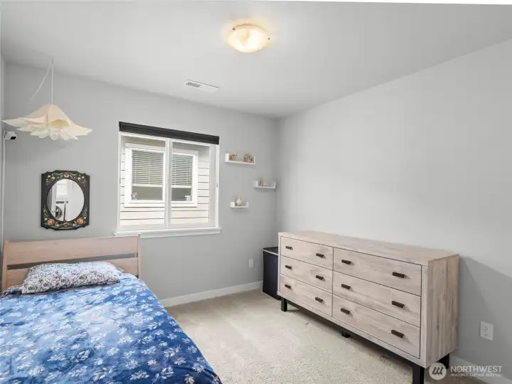 Comfortable 1st bedroom with plush carpet, natural light, and charming decorative touches.