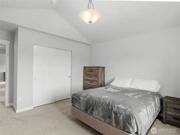 Second view of Bedroom 4 showcases the vaulted ceiling detail, double sliding closet with upgraded panel doors, and ample room for a full furniture set. A welcoming retreat with a warm, airy feel.