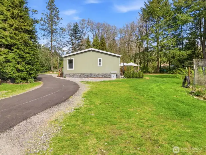 Paved circular driveway, parking area and garden space on the right.