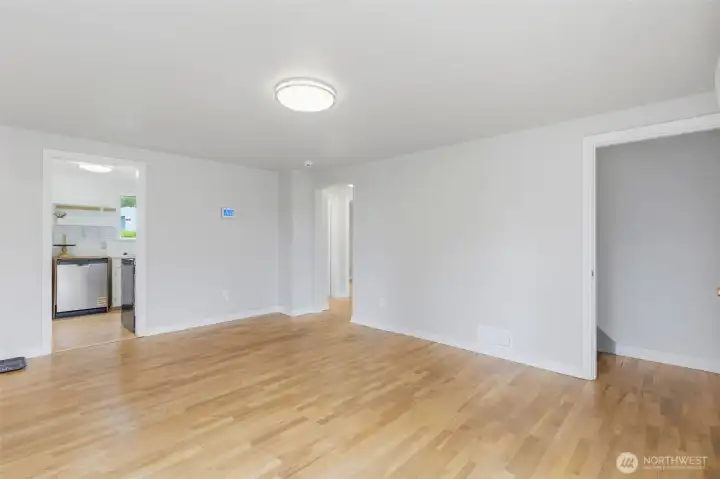 Living room with kitchen to the left, hallway in center that leads to 2 bedrooms and bath, and stairs to basement. Doorway on the right heads upstairs to another finished room