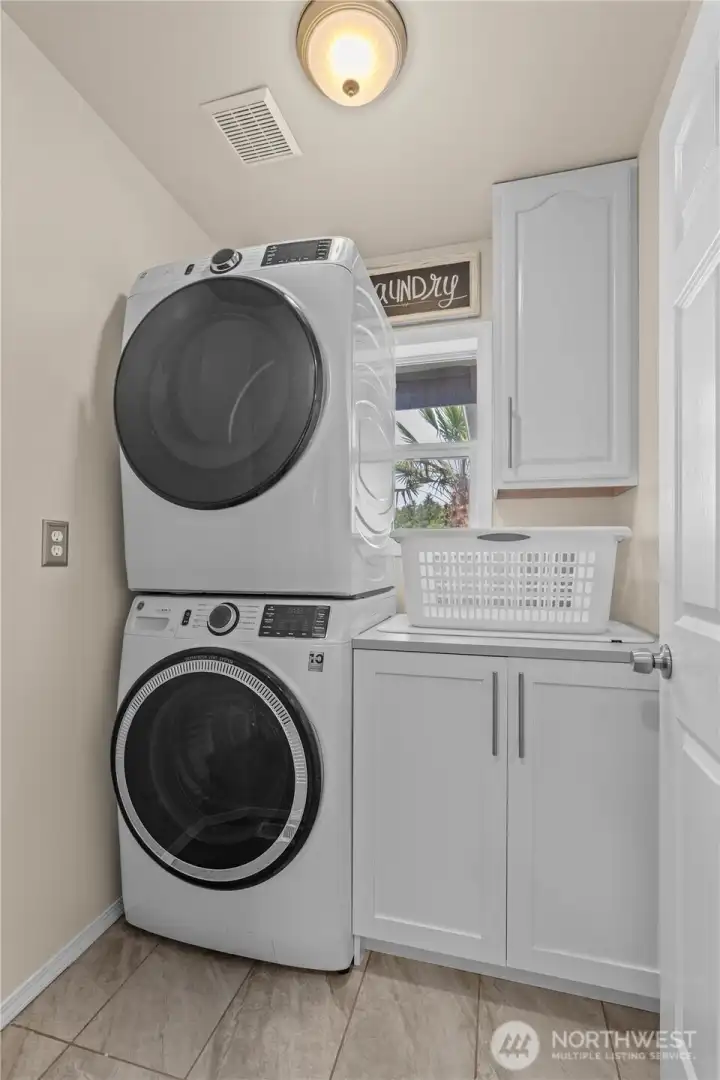 Laundry Room with Built In Cabinets and Stackable Washer and Dryer.