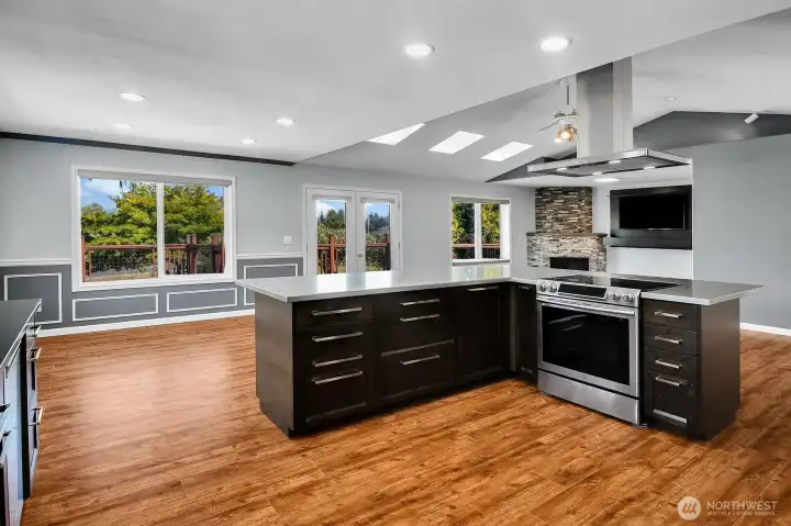 The spacious, open-concept kitchen flows seamlessly into the dining area and family room. The French doors open to the expansive wraparound deck, extending the living space outdoors. The spacious, open-concept kitchen flows seamlessly into the dining area and family room. The French doors open to the expansive wraparound deck, extending the living space outdoors.