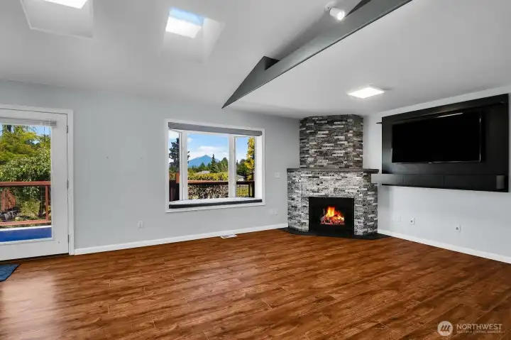 Gather around the cozy fireplace while taking in the stunning views of Mt. Pilchuck through the expansive window, creating a warm and inviting living space you'll enjoy year-round. Gather around the cozy fireplace while taking in the stunning views of Mt. Pilchuck through the expansive window, creating a warm and inviting living space you'll enjoy year-round.