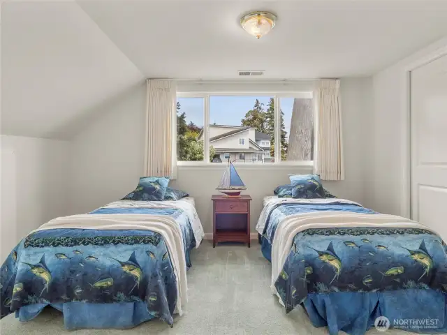 This is bedroom number three, which is large enough to fit two twin sized beds comfortably. In addition to the closet, there is a large storage space to the left of the left bed.