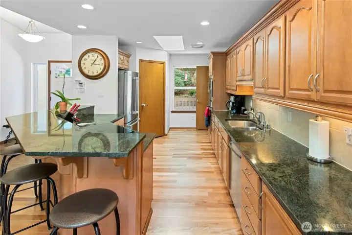 Spacious Kitchen with plenty of storage and pantry.  Slab counters, wood floors, under cabinet counter lighting.