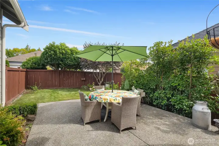 Private extended back patio with a side yard that features a rose and vegetable garden.